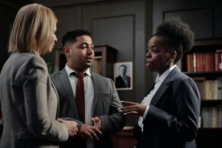 Three very well dressed attorney talking in a circle.