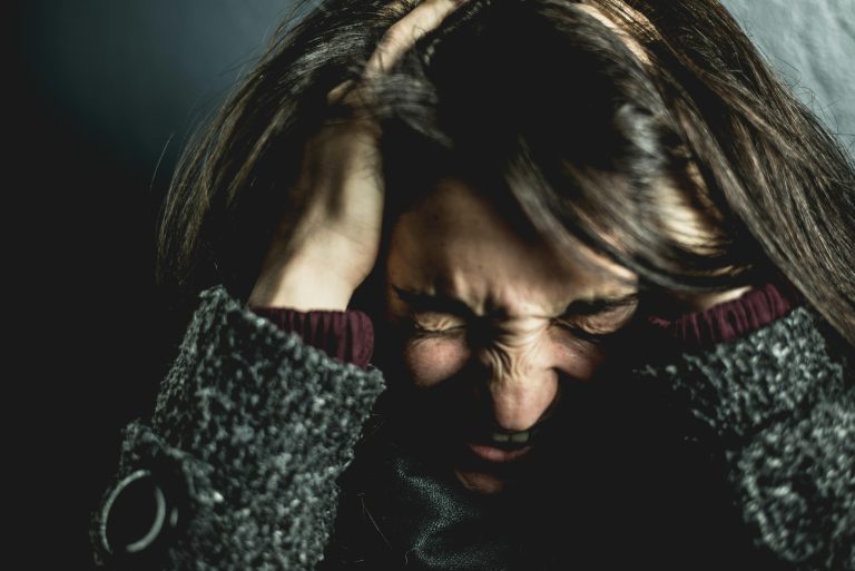 Close-up of a distressed woman holding her head in frustration, expressing the emotional overwhelm that can come with first time homeownership stress and anxiety.