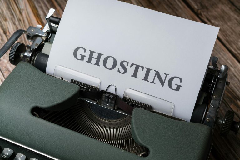 Close-up of a vintage typewriter with a sheet of paper displaying the word "GHOSTING" in bold letters, symbolizing the concept of being ignored or cut off without explanation.
