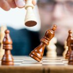 Chess board game. One piece is knocking over another piece.