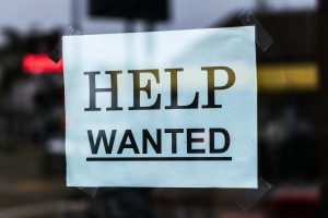 Sign in a window that says help wanted.