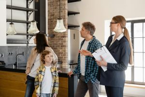 real estate agent shows a modern kitchen to a family with a young child during a home tour.