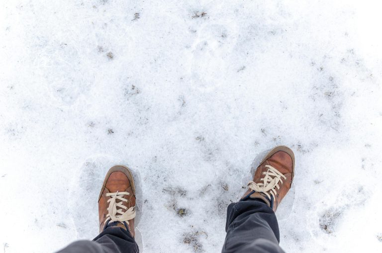 Person standing on snow-covered ground in brown sneakers, symbolizing the feeling of cold feet during a major decision like buying a home.