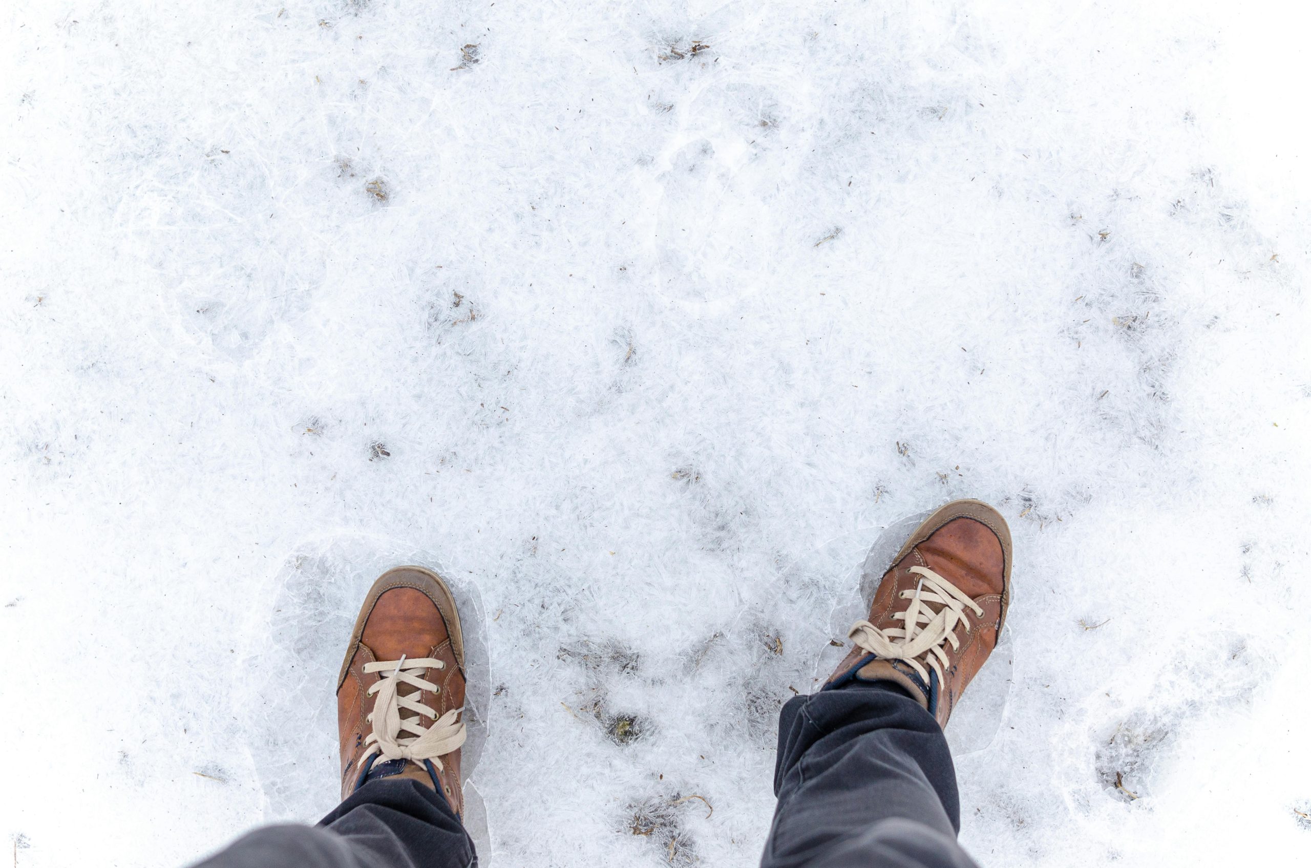 Person standing on snow-covered ground in brown sneakers, symbolizing the feeling of cold feet during a major decision like buying a home.