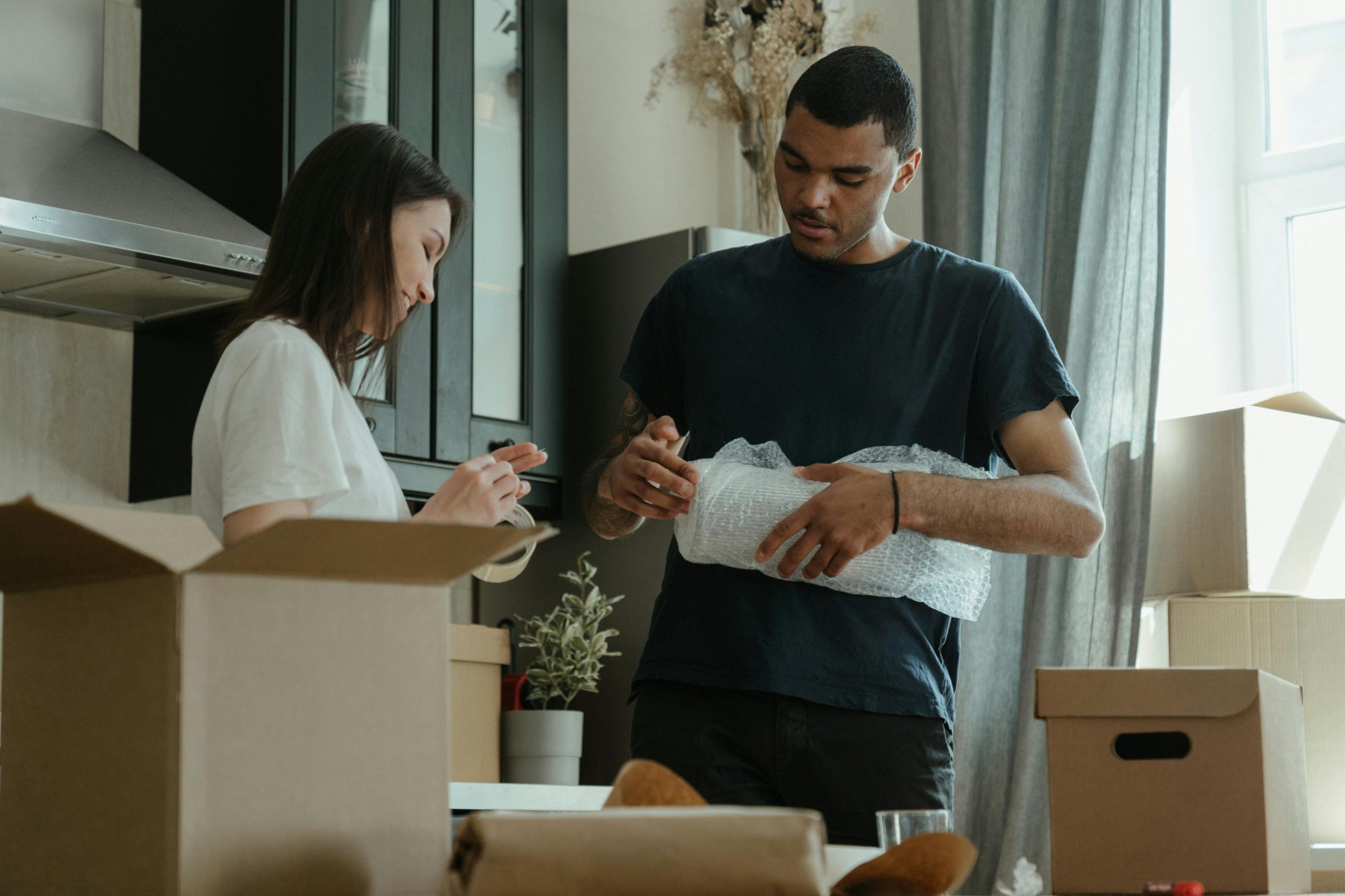 - Unbiased Real Estate Advice: The Truth About Real Estate A couple packing items into cardboard boxes in a kitchen, wrapping fragile belongings in bubble wrap during a move.