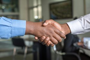 Close-up of two people shaking hands in an office setting, symbolizing a signed real estate agreement