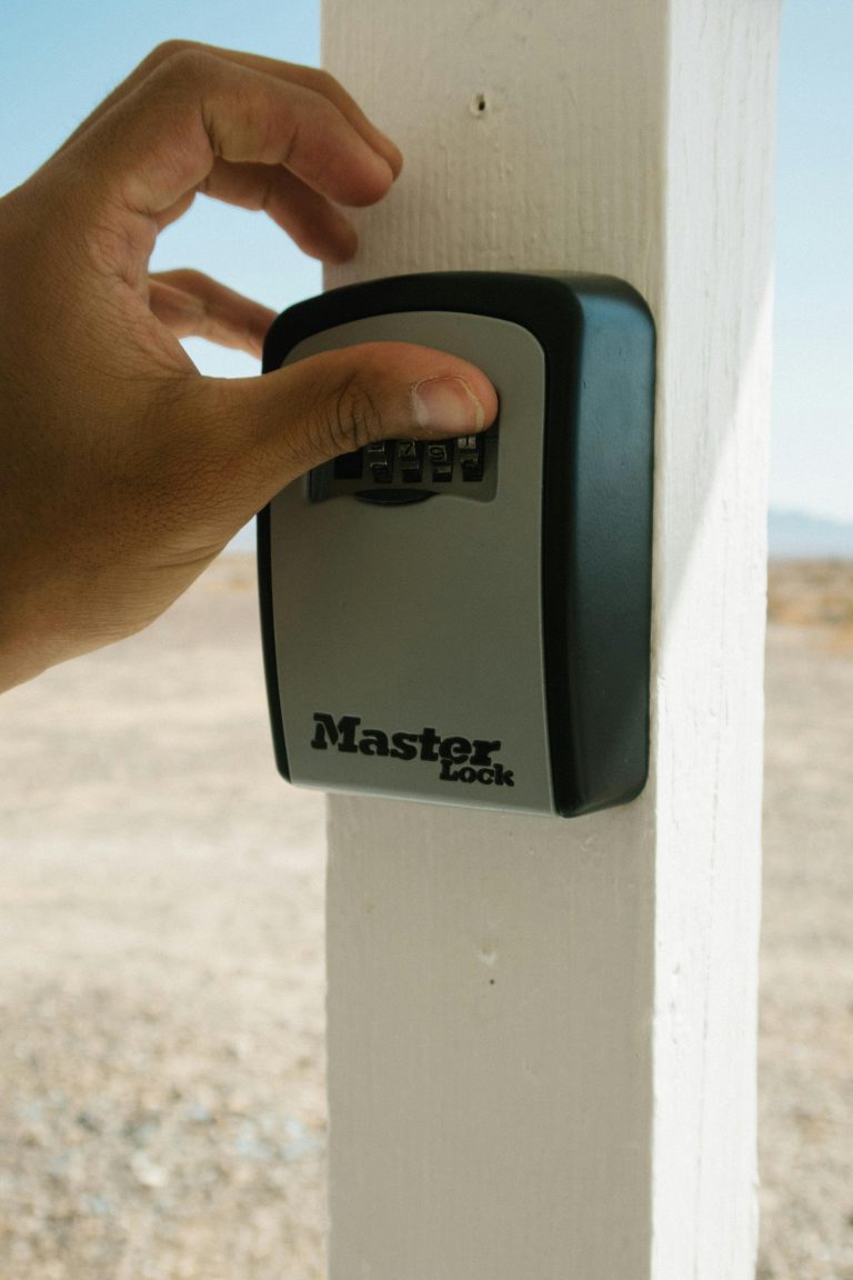 Close up of a hand entering a code on a lockbox mounted to a post, illustrating unsecured access risks and the need for supervised showings.