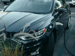 Electric car connected to a charger in a parking lot, highlighting the importance of confirming charger inclusions when buying a home.