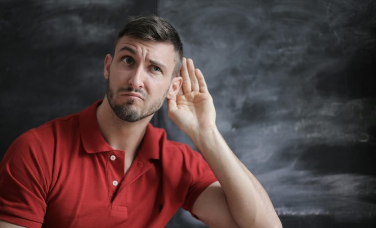 Man holding his hand to his ear in a listening gesture symbolizing the importance of feedback when selling a home.
