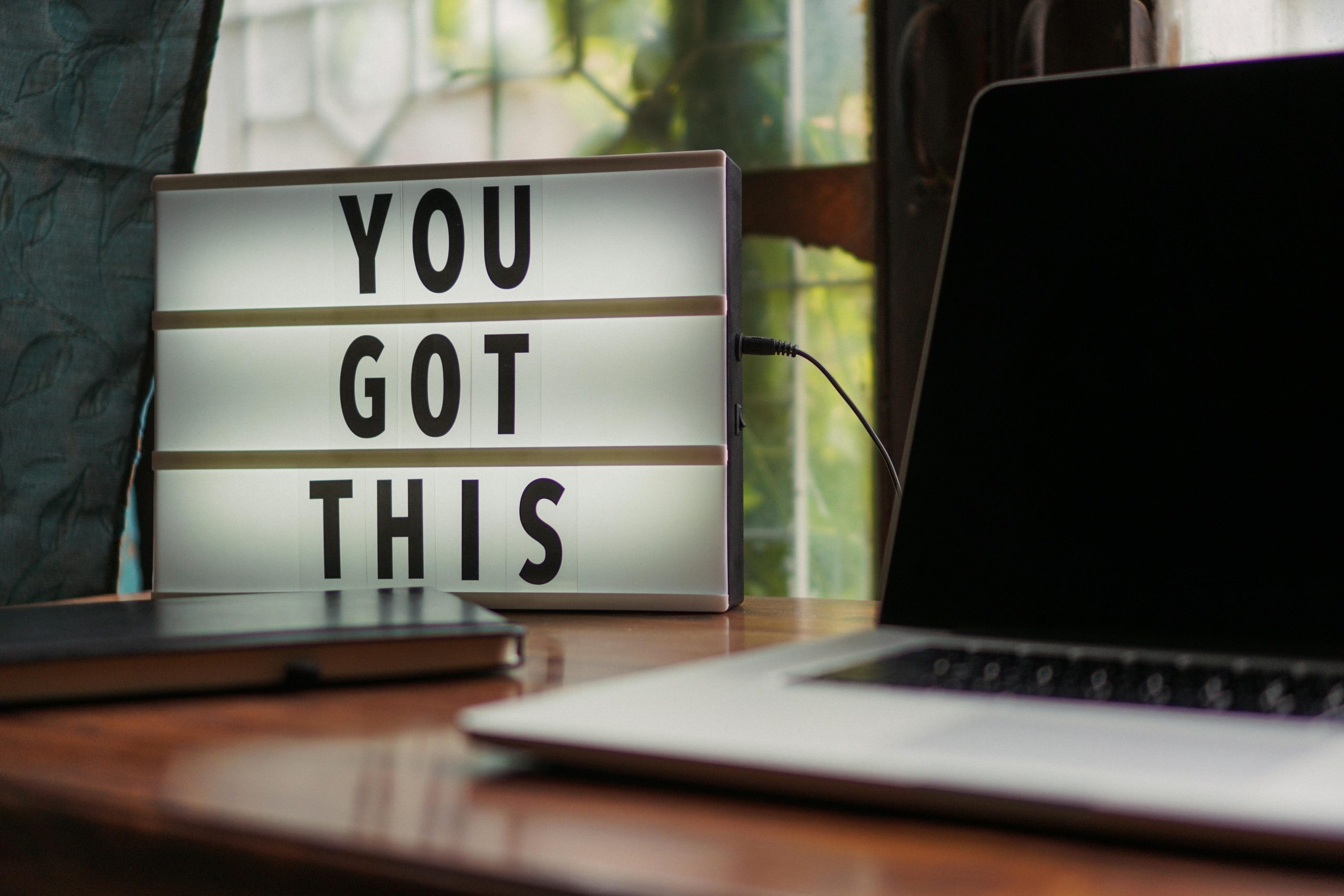 A motivational lightbox sign reading You Got This on a desk beside a laptop, symbolizing encouragement for sellers not to take their home off the market.