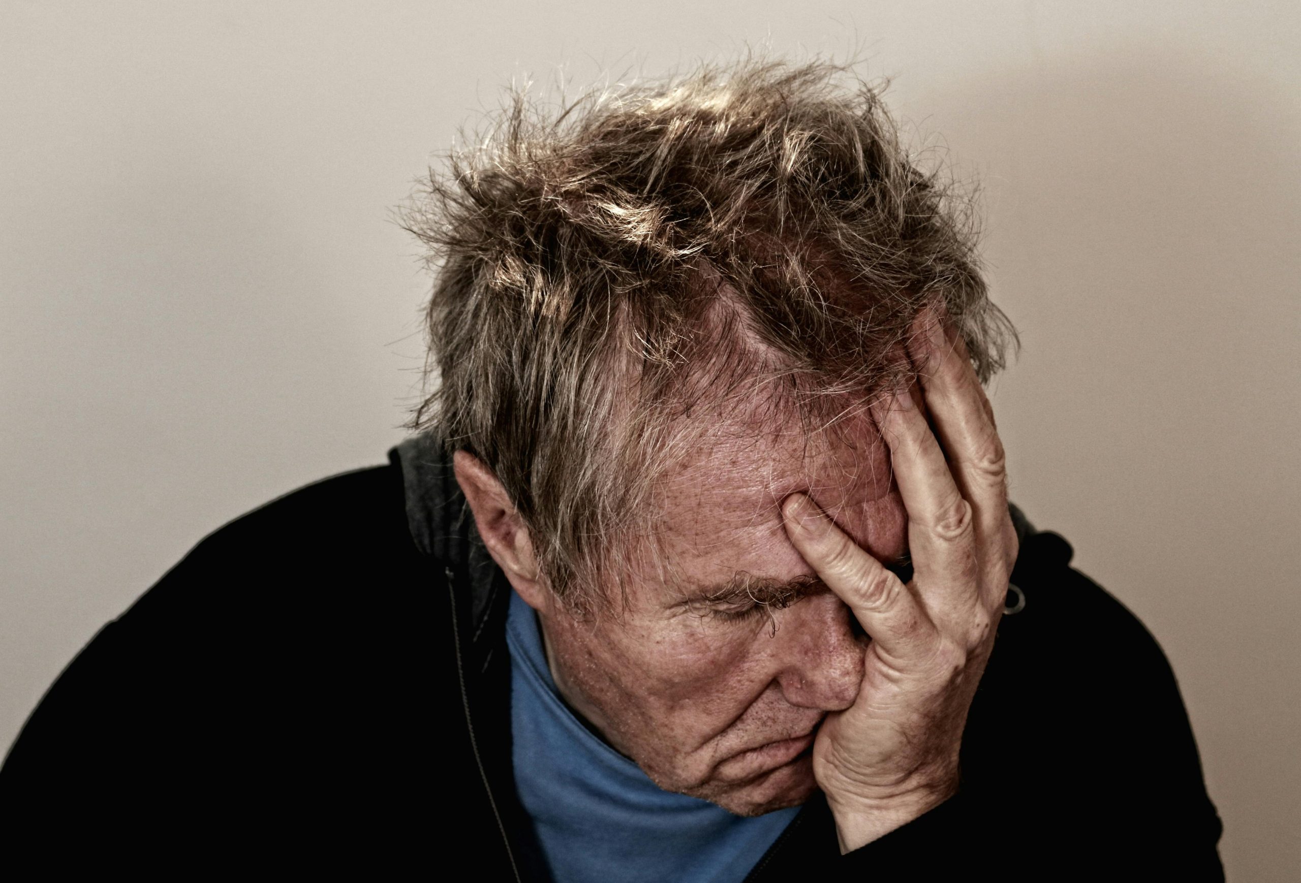 - Unbiased Real Estate Advice: The Truth About Real Estate Stressed older man with his hand on his face looking down, showing anxiety and frustration related to a slow home sale.