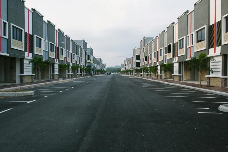 - Unbiased Real Estate Advice: The Truth About Real Estate Wide view of a modern condo community with rows of townhome style buildings and empty parking spaces along a central street.