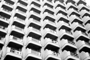 Black and white view of a high rise condo building with repeating balconies forming a grid pattern across the facade.