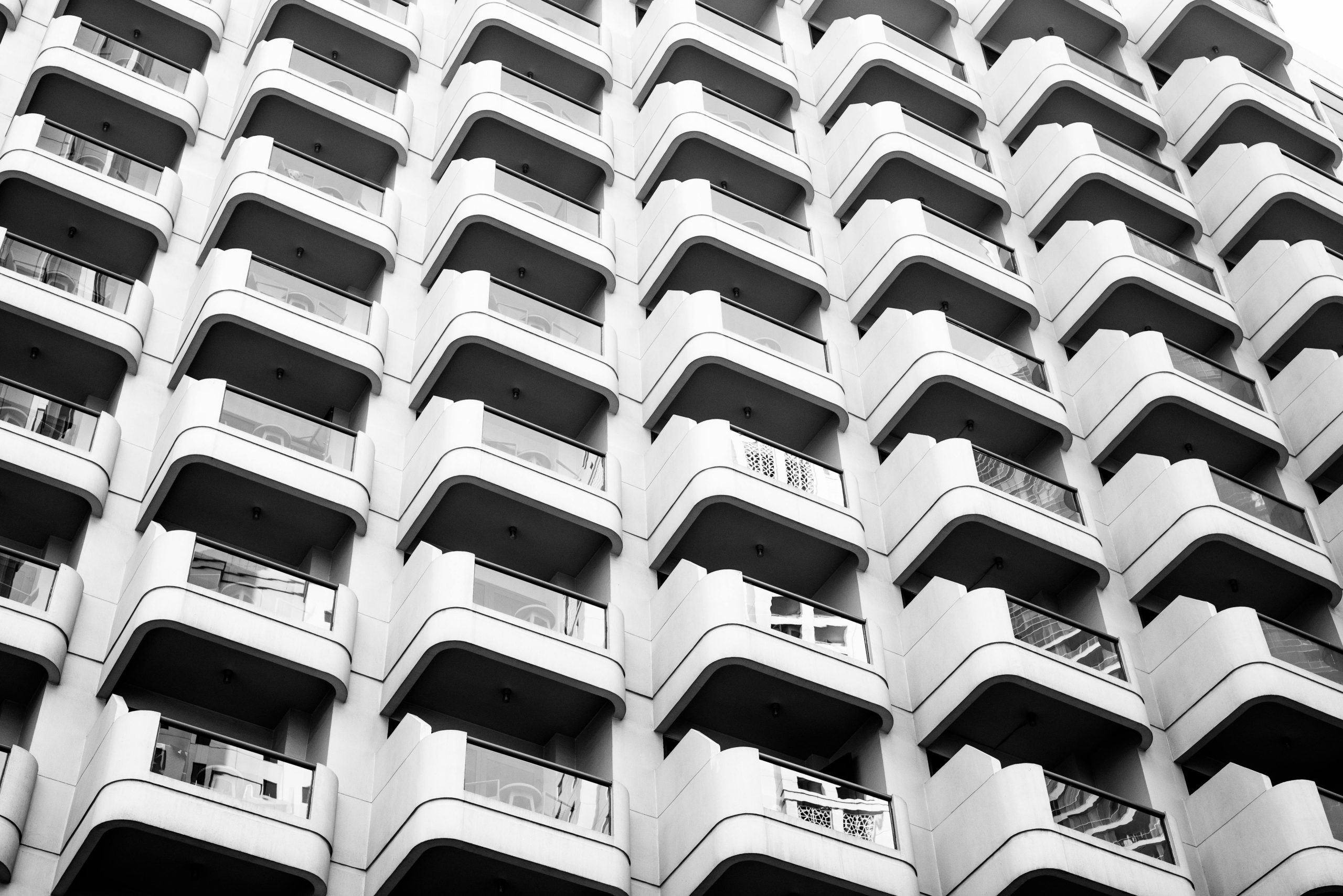 - Unbiased Real Estate Advice: The Truth About Real Estate Black and white view of a high rise condo building with repeating balconies forming a grid pattern across the facade.