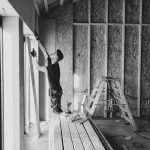 Contractor installing drywall inside a framed new home, highlighting new construction incentives like rate buydowns, upgrade credits, and closing cost help.